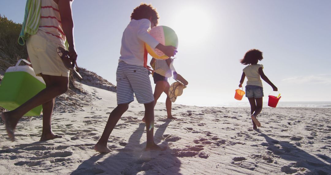 Family playing on beach with sand buckets on sunny day - Free Images, Stock Photos and Pictures on Pikwizard.com