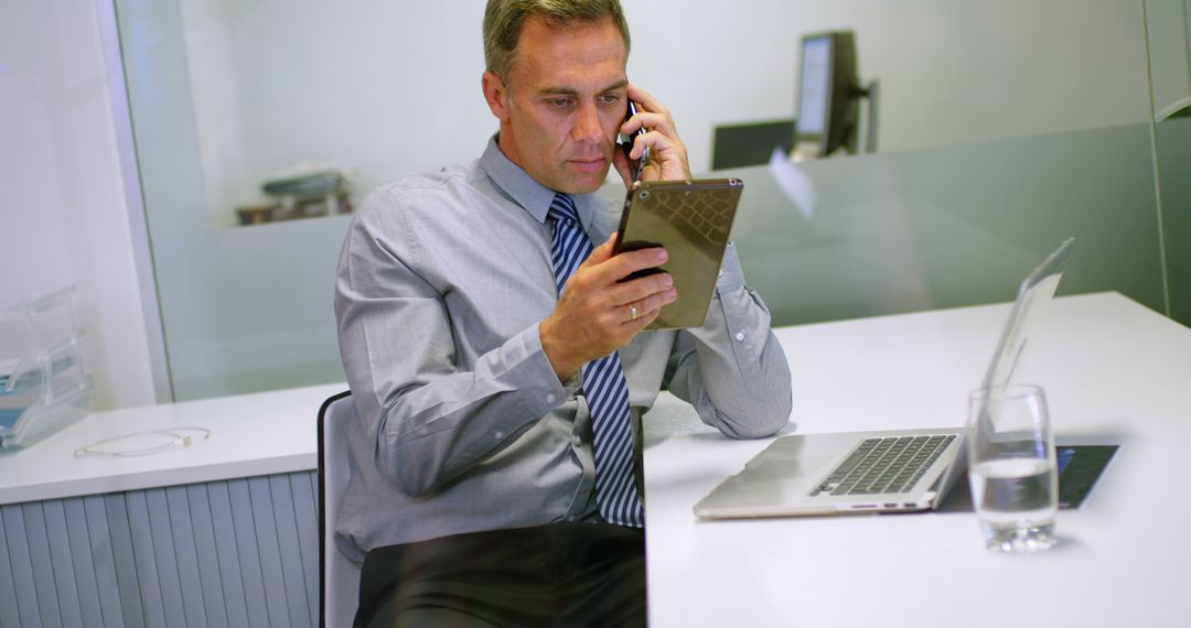 Focused Businessman in Office Using Tablet and Smartphone - Free Images, Stock Photos and Pictures on Pikwizard.com