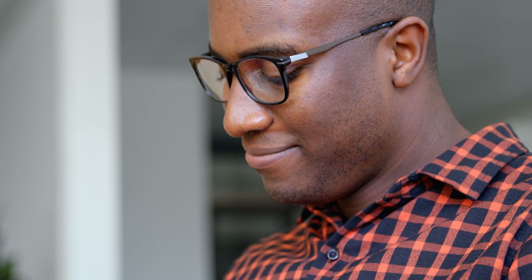 Thoughtful Man in Plaid Shirt Smiling and Wearing Glasses