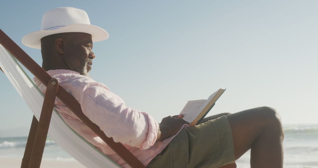 Elderly Man Enjoying Reading Book on Sunny Beach