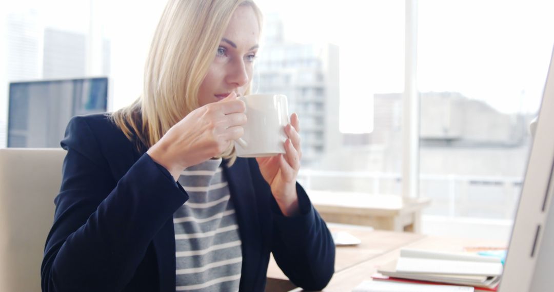 Businesswoman Drinking Coffee While Working on Computer in Office - Free Images, Stock Photos and Pictures on Pikwizard.com