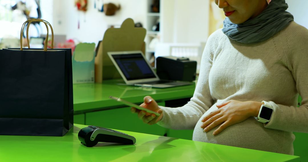 Pregnant Woman Makes Mobile Payment at Store Counter - Free Images, Stock Photos and Pictures on Pikwizard.com