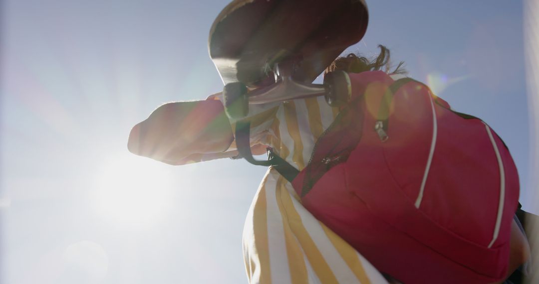 Low Angle of Person Holding Skateboard Against Bright Blue Sky - Free Images, Stock Photos and Pictures on Pikwizard.com