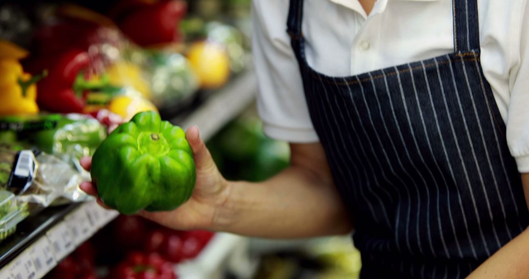 Grocery Store Worker Holding Fresh Green Bell Pepper - Free Images, Stock Photos and Pictures on Pikwizard.com