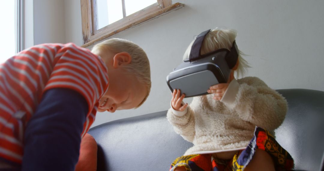 Young Siblings Using Virtual Reality Headset on Sofa at Home