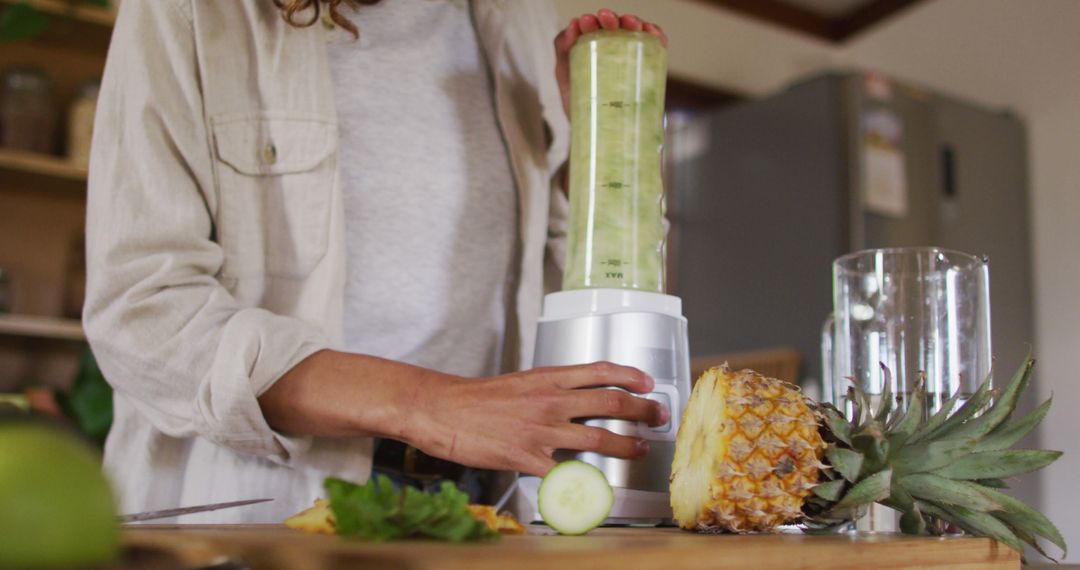 Woman Making Smoothie in Kitchen with Fresh Pineapple and Cucumber - Free Images, Stock Photos and Pictures on Pikwizard.com