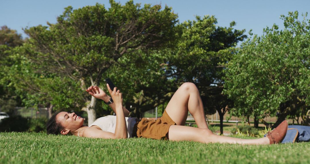 Young Woman Relaxing on Grass Using Smartphone in Park - Free Images, Stock Photos and Pictures on Pikwizard.com