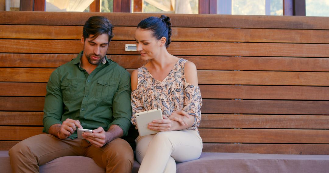 Couple Engaging with Technology on Wooden Bench