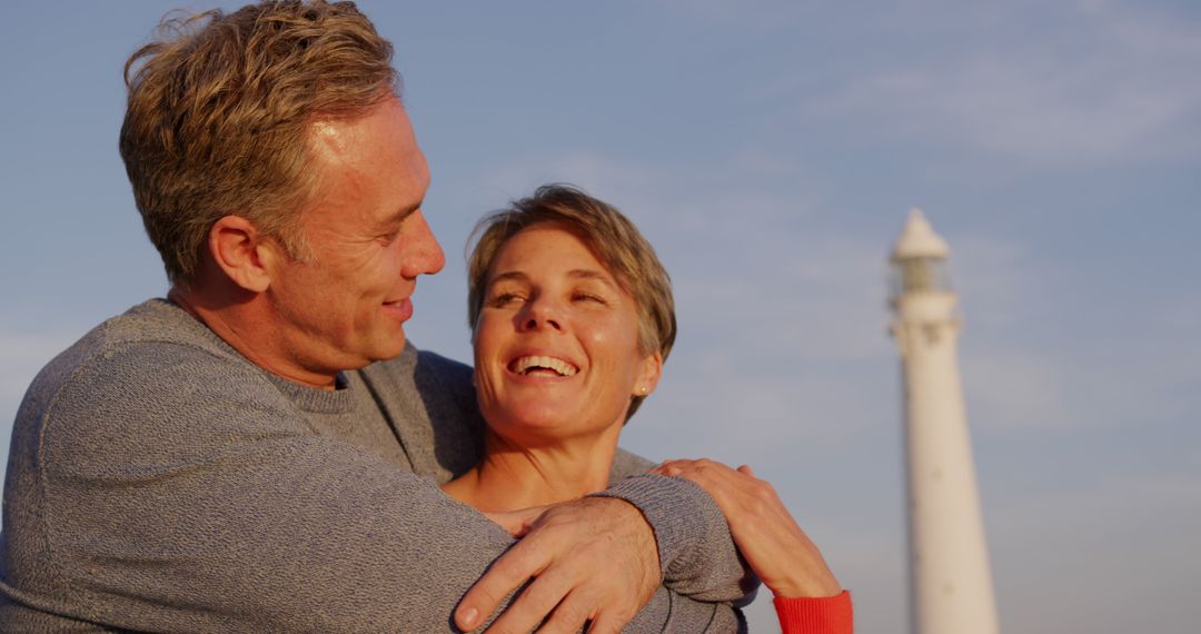 Senior Couple Embracing Near Lighthouse at Dusk