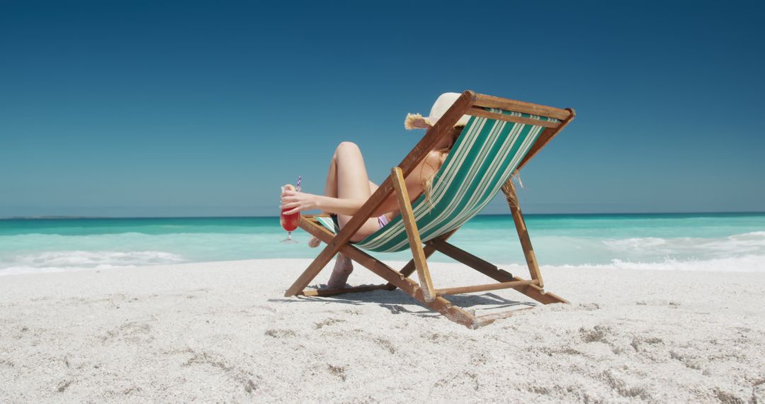 Relaxing Beach Scene with Woman in Deckchair Sipping Cocktail - Free Images, Stock Photos and Pictures on Pikwizard.com