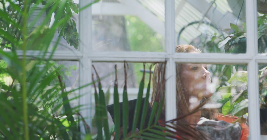 Woman Relaxing in Greenhouse Surrounded by Lush Foliage - Free Images, Stock Photos and Pictures on Pikwizard.com