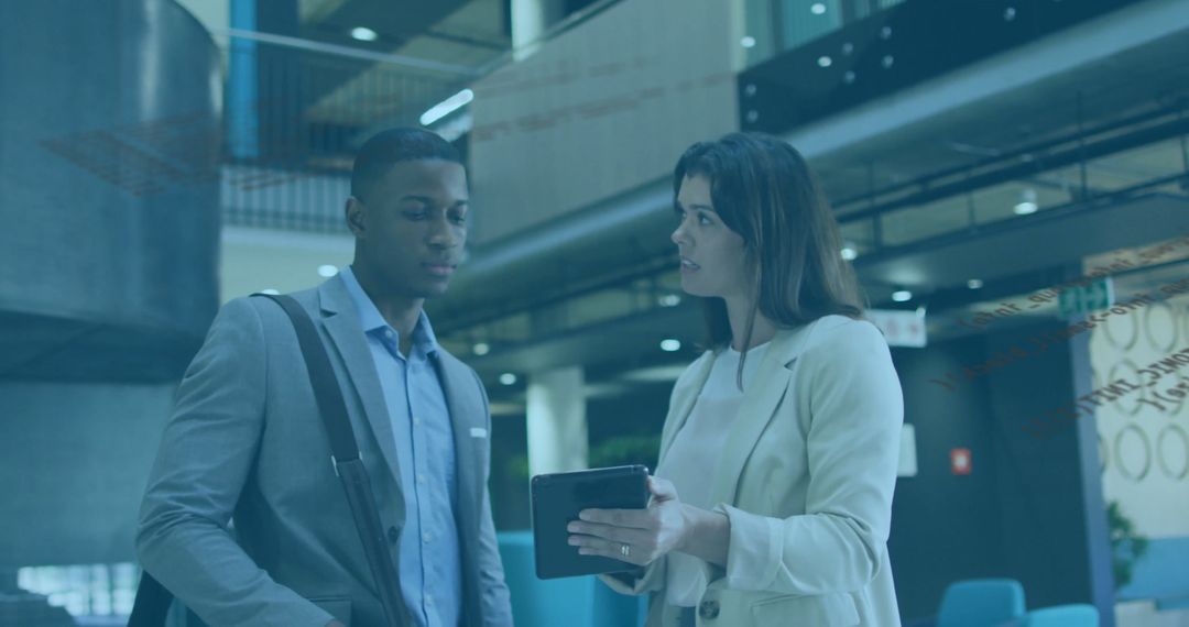 Business Colleagues Discussing on Tablet in Modern Lobby