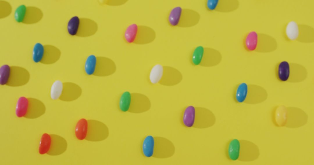 Image of overhead view of rows of multi coloured sweets over yellow background - Free Images, Stock Photos and Pictures on Pikwizard.com
