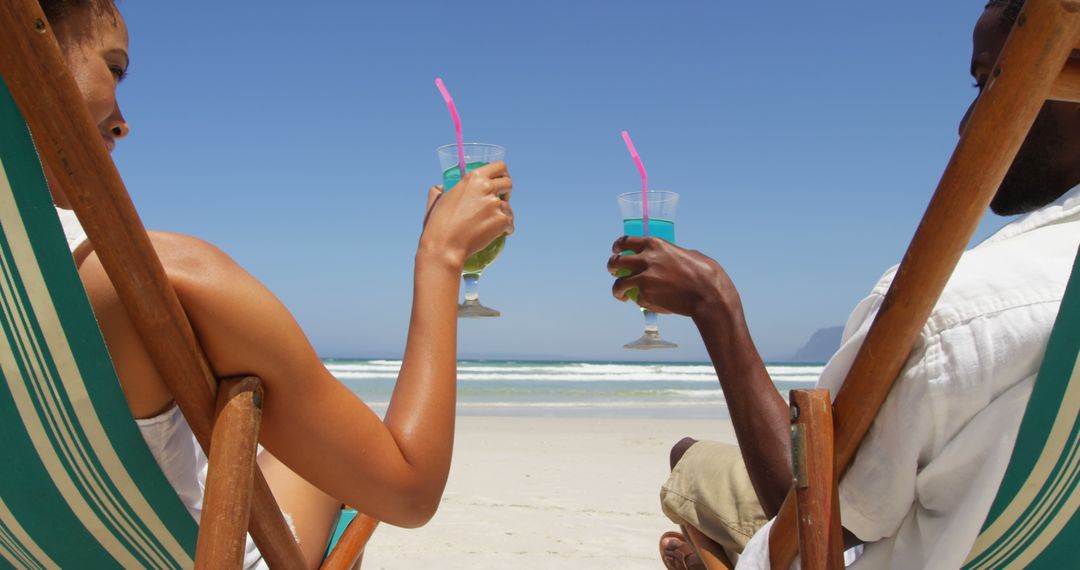 Young Couple Toasting with Drinks on Sunny Beach - Free Images, Stock Photos and Pictures on Pikwizard.com