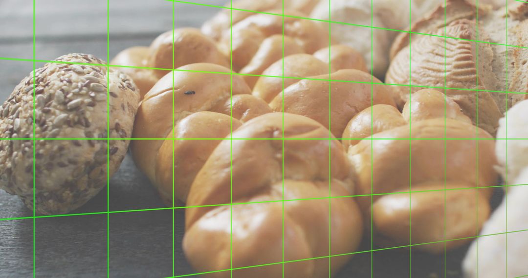 Braided challah loaf with seeded roll on dark wood surface with green grid overlay