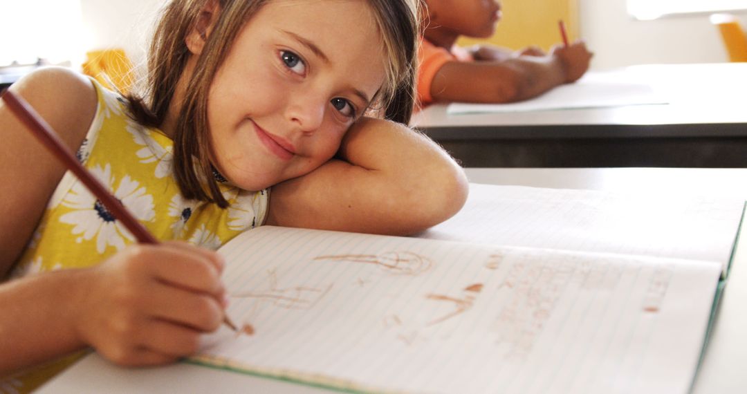 Young Girl Smiling While Writing in Classroom - Free Images, Stock Photos and Pictures on Pikwizard.com