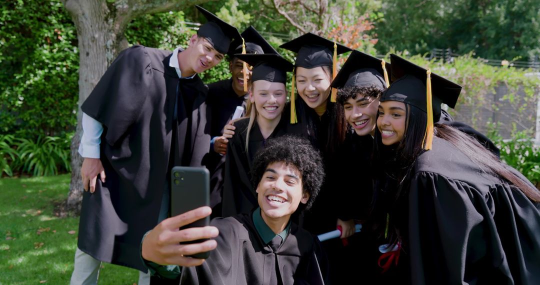 Multiracial Graduates Taking Selfie While Celebrating Commencement on Campus Lawn