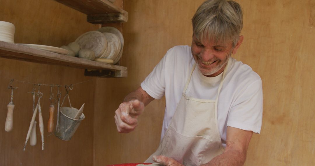 Smiling Senior Man Creating Pottery on Wheel in Workshop