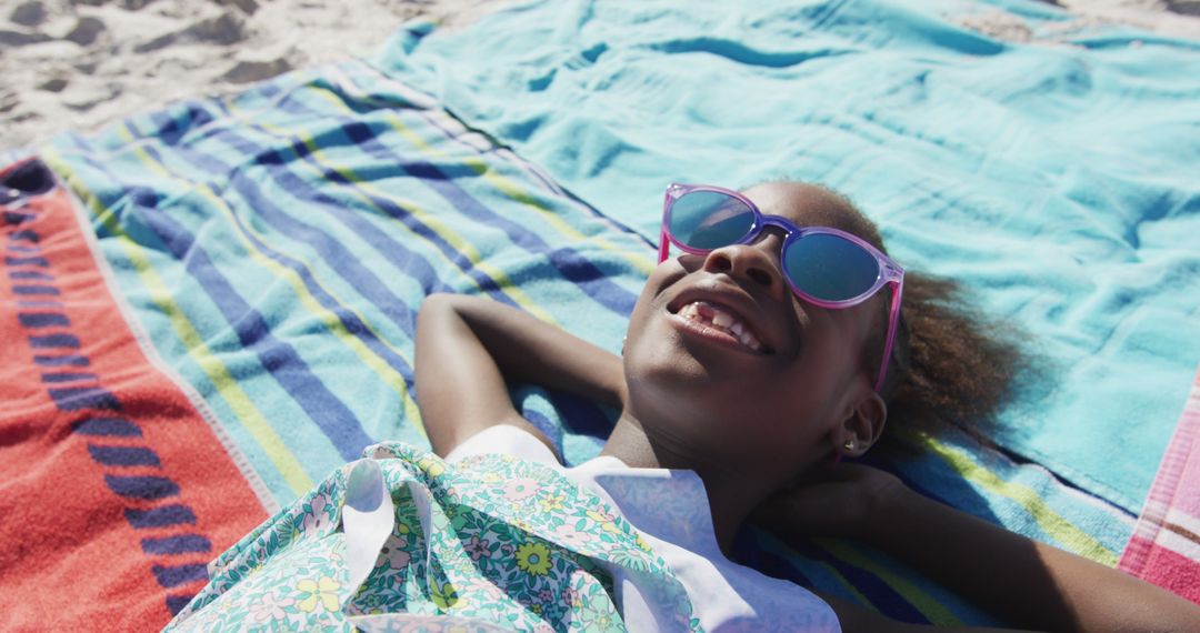 Happy Girl Relaxing on Beach with Colorful Blankets and Sunglasses - Free Images, Stock Photos and Pictures on Pikwizard.com