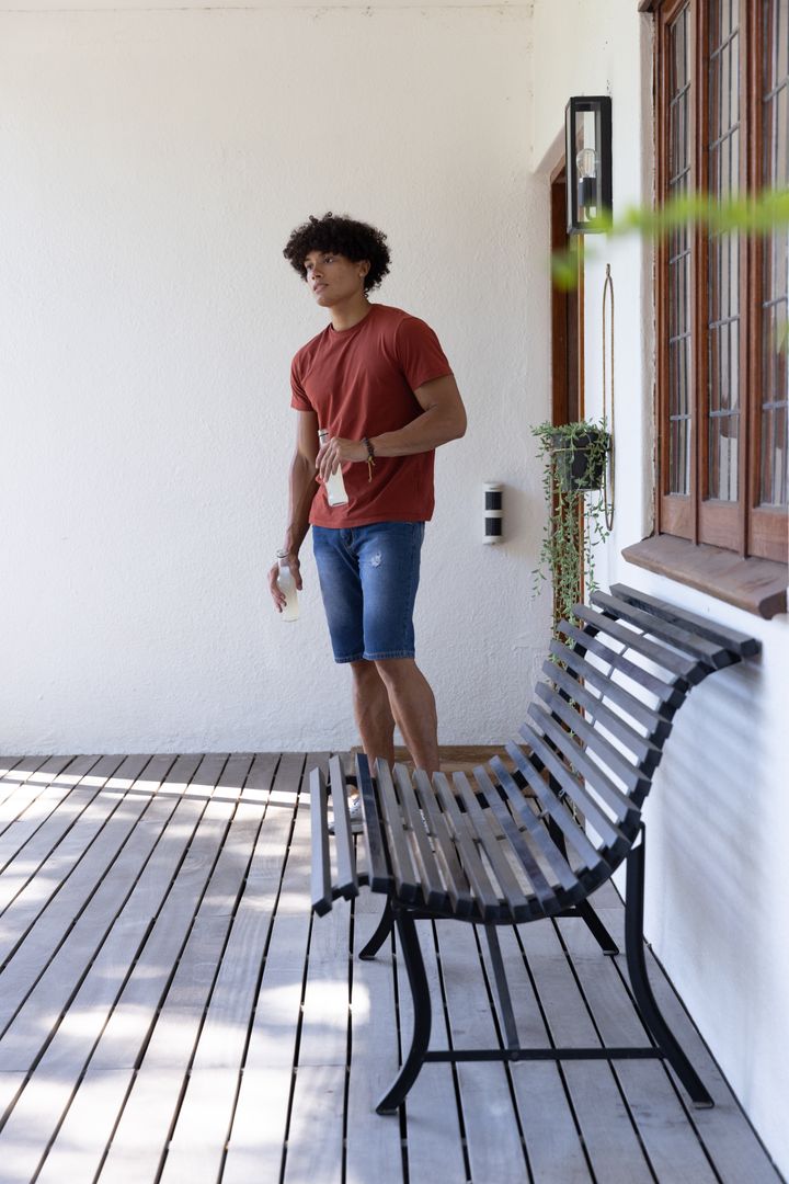 Man Enjoys Leisure Time on Sunny Wooden Deck with Glasses of Refreshing Beverage