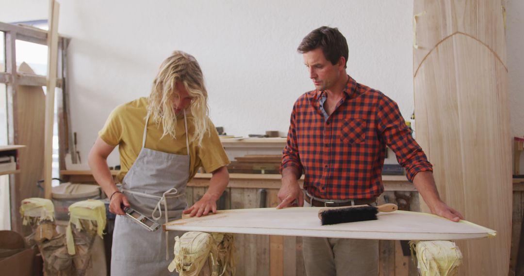 Two Men Working on Crafting Wooden Surfboard in Workshop - Free Images, Stock Photos and Pictures on Pikwizard.com