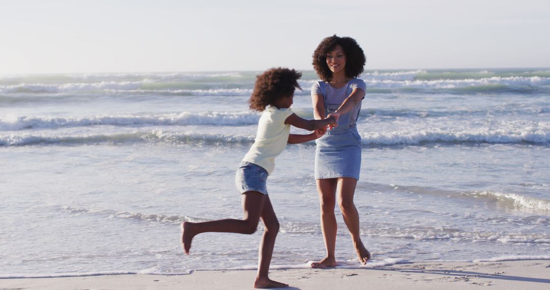 African american mother and her daughter playing on the beach - Free Images, Stock Photos and Pictures on Pikwizard.com