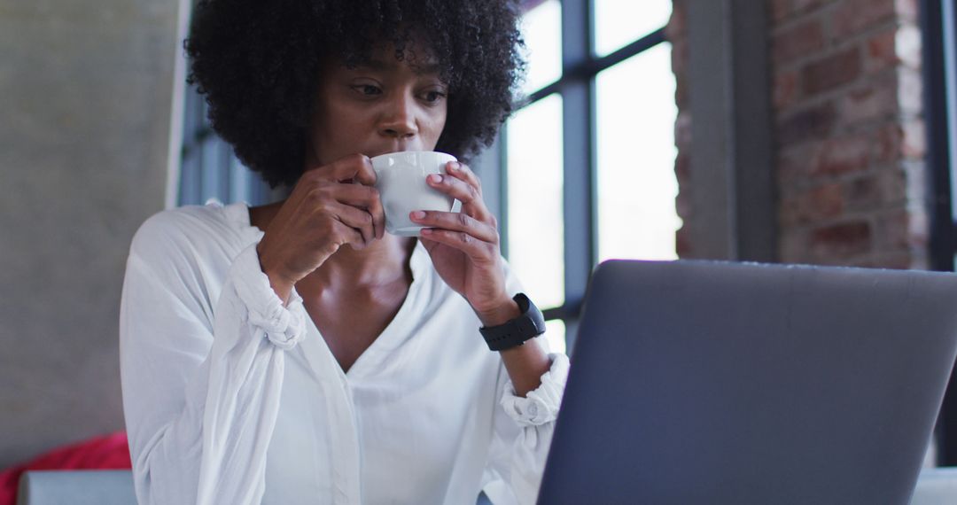 Focused African American Woman Drinking Coffee Working on Laptop - Free Images, Stock Photos and Pictures on Pikwizard.com