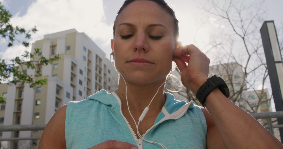 Focused Female Athlete Adjusting Earphones for Outdoor Workout - Free Images, Stock Photos and Pictures on Pikwizard.com