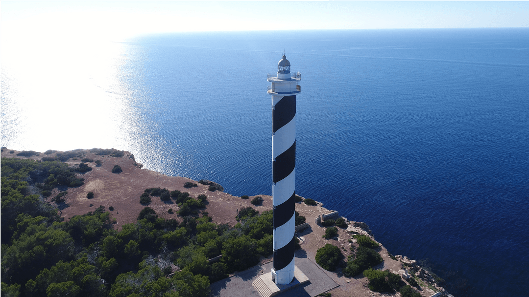 Scenic View of Striped Lighthouse on Rocky Coastline with Vast Ocean