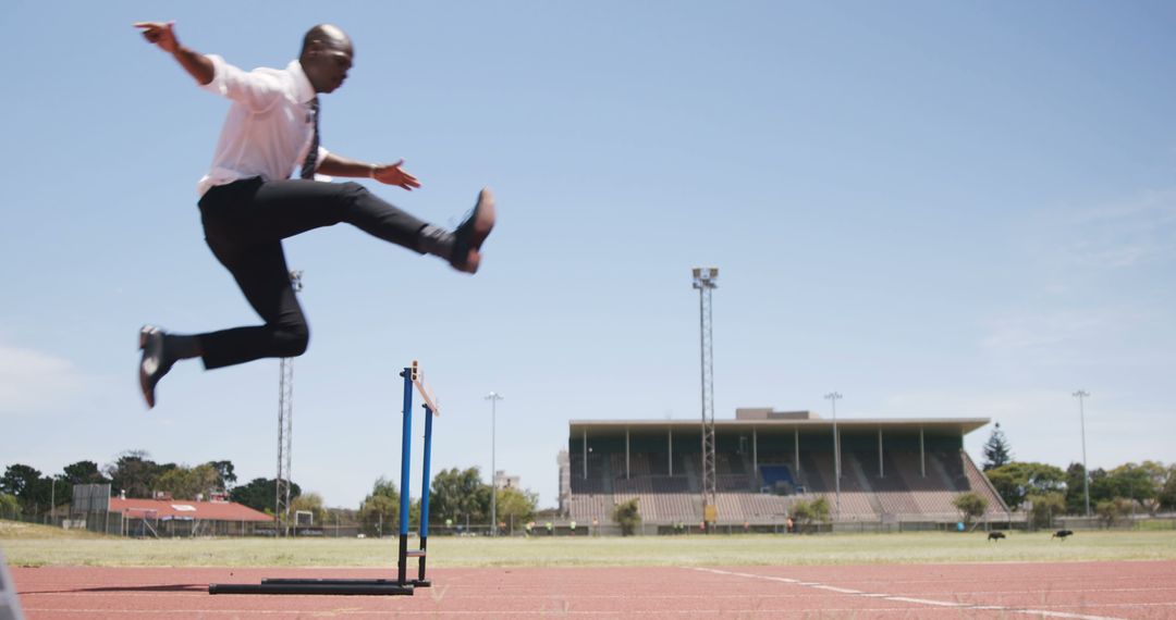 Businessman Jumping Over Hurdle In Stadium - Free Images, Stock Photos and Pictures on Pikwizard.com