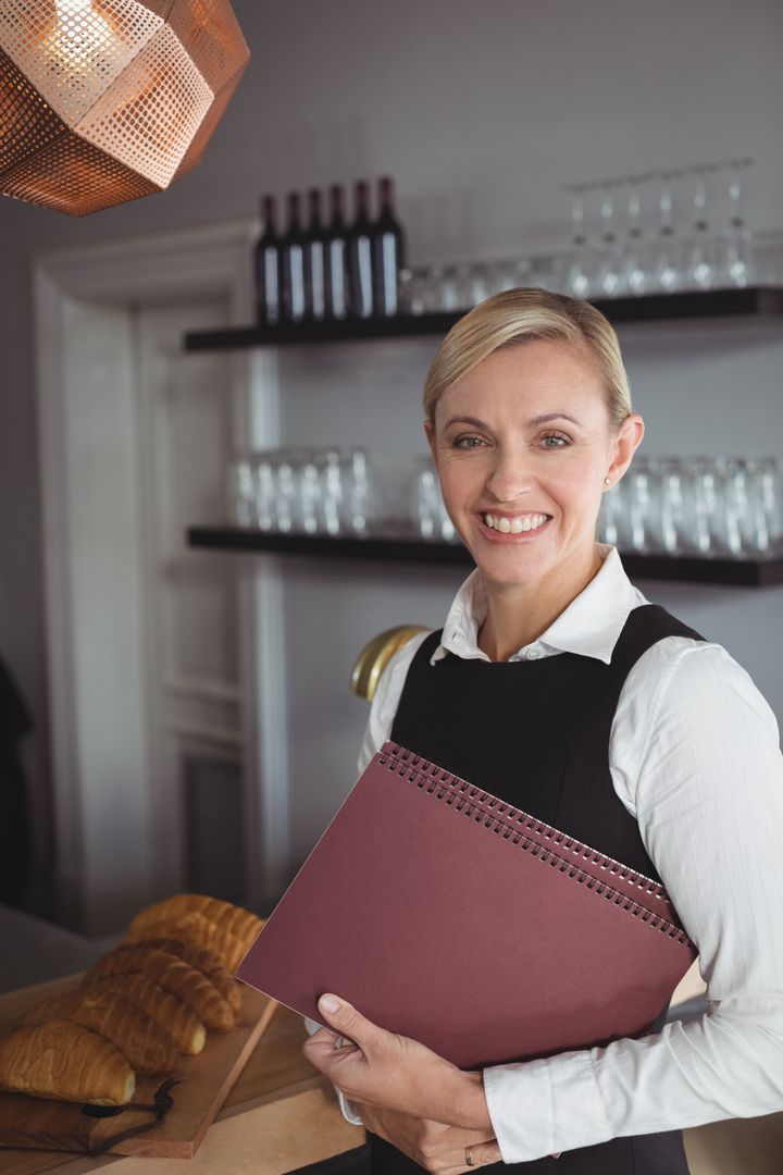 Smiling Waitress Holding Menu Card in Restaurant - Free Images, Stock Photos and Pictures on Pikwizard.com