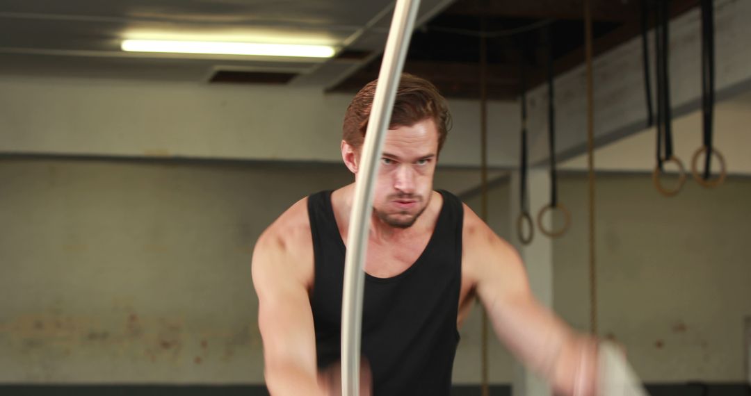 Caucasian Man Exercising with Battle Ropes in Gym
