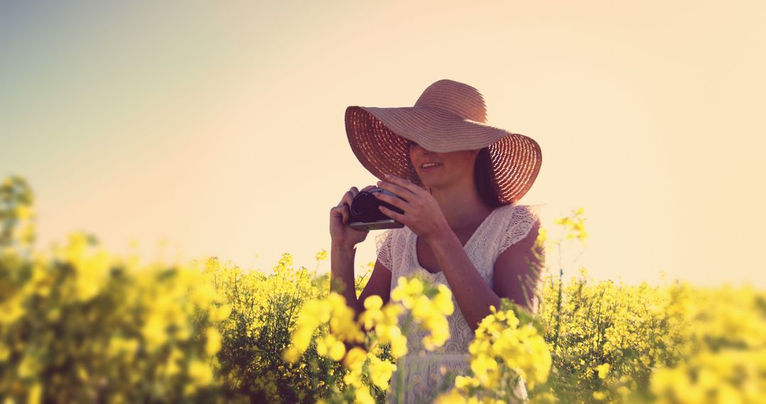 A woman enjoys her photography hobby in a picturesque yellow flower field. - Free Images, Stock Photos and Pictures on Pikwizard.com