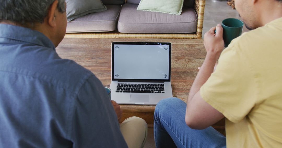 Two People Looking at Laptop Screen While Drinking Coffee in Living Room - Free Images, Stock Photos and Pictures on Pikwizard.com