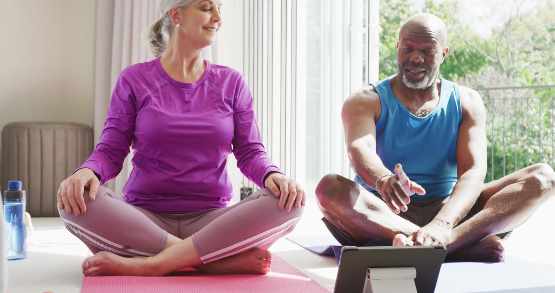 Happy Senior Couple Practicing Yoga at Home with Tablet
