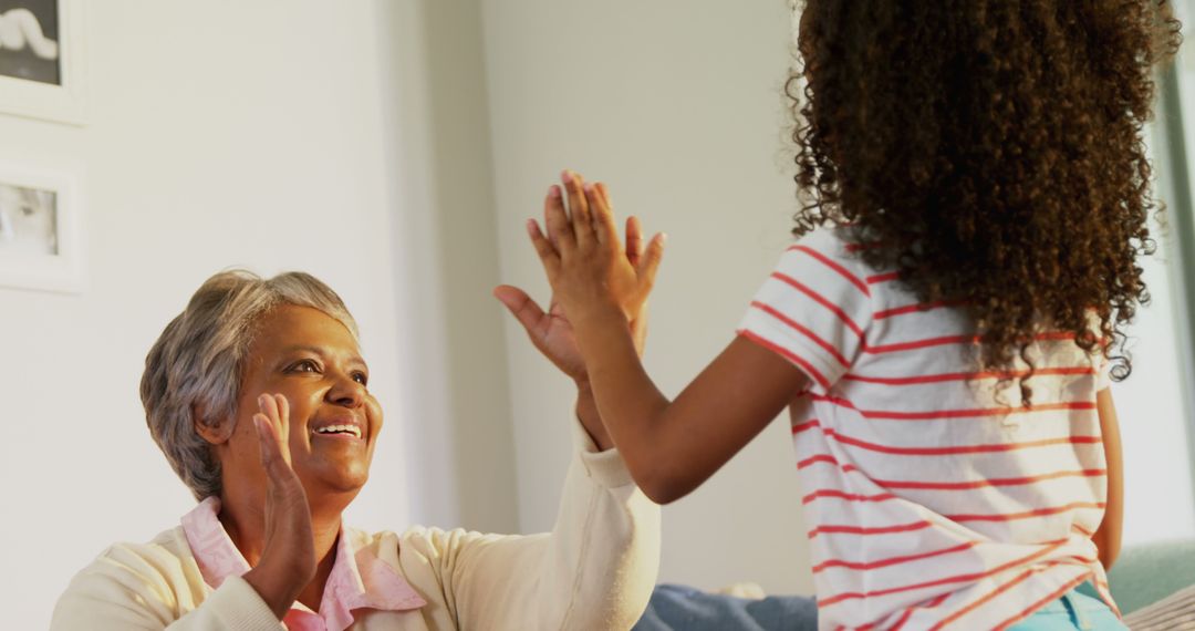 Senior Woman High-Fiving Granddaughter at Home - Free Images, Stock Photos and Pictures on Pikwizard.com