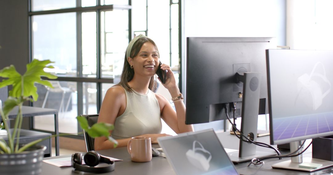 Smiling Woman Talking on Phone While Working at Modern Office Desk