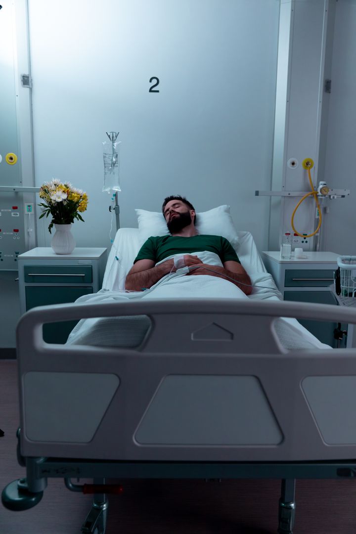 Male Patient Resting in Hospital Bed in Dimly Lit Room - Free Images, Stock Photos and Pictures on Pikwizard.com