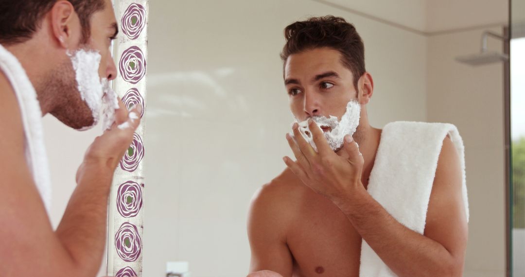 Young man shaving and checking his reflection in bathroom mirror - Free Images, Stock Photos and Pictures on Pikwizard.com