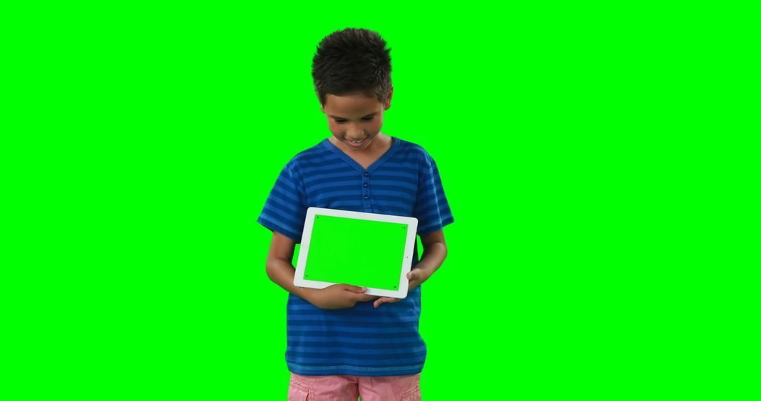 A young boy stands against a green screen holding a tablet with a green screen, with copy space - Free Images, Stock Photos and Pictures on Pikwizard.com