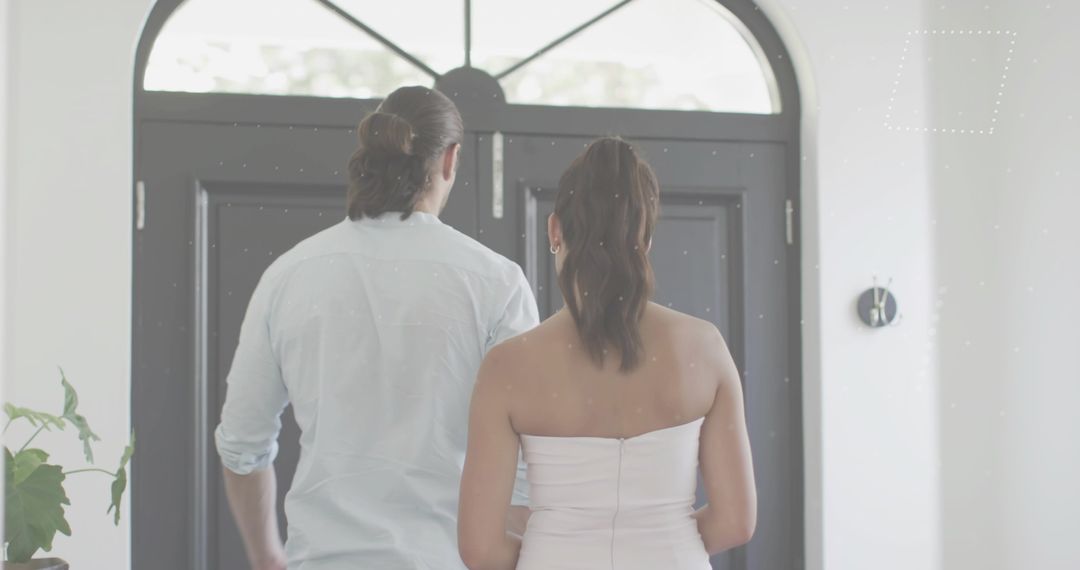 Couple entering foyer through black double doors with arched transom and natural light