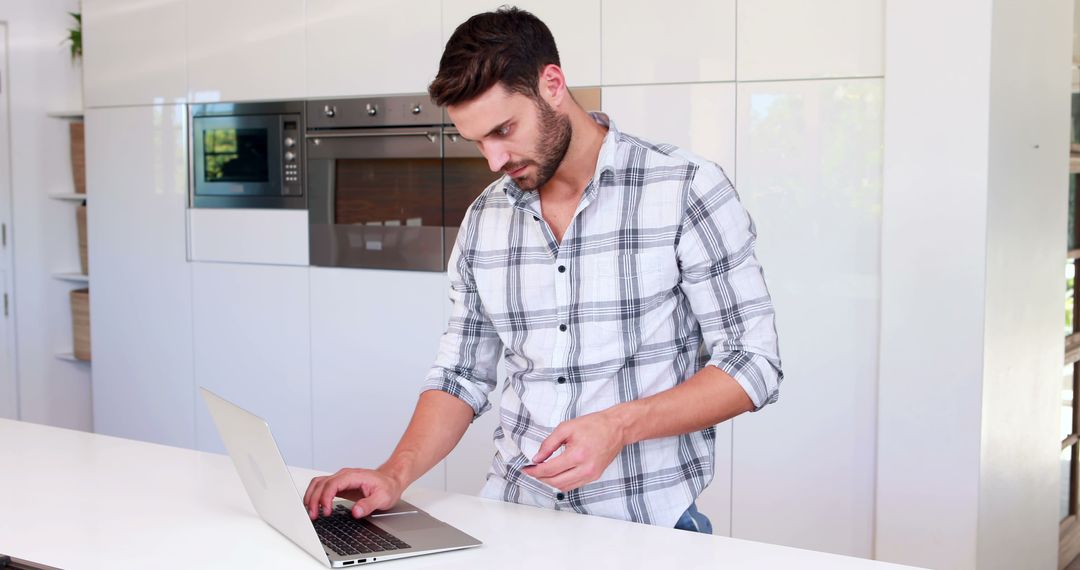 Man Working on Laptop in Modern Kitchen - Free Images, Stock Photos and Pictures on Pikwizard.com