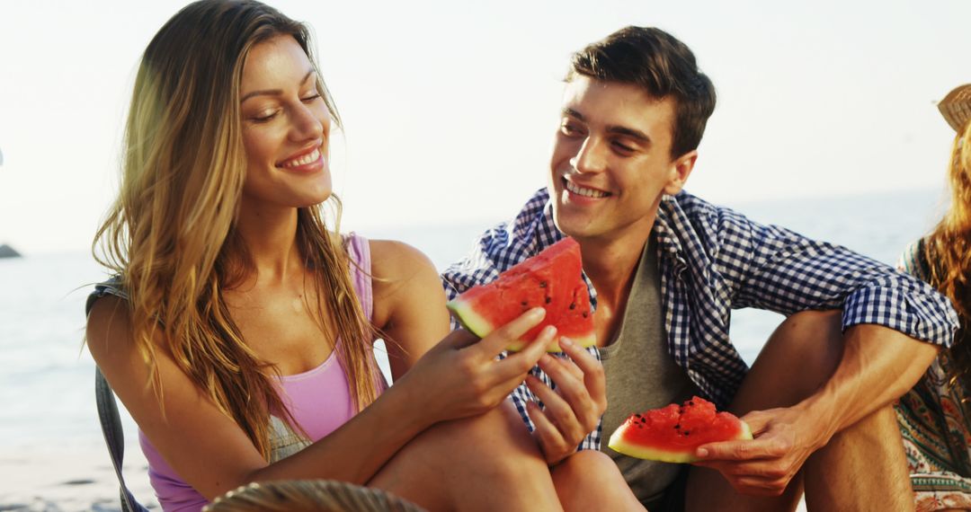 Happy caucasian couple eating watermelon with friends in the sun at beach - Free Images, Stock Photos and Pictures on Pikwizard.com