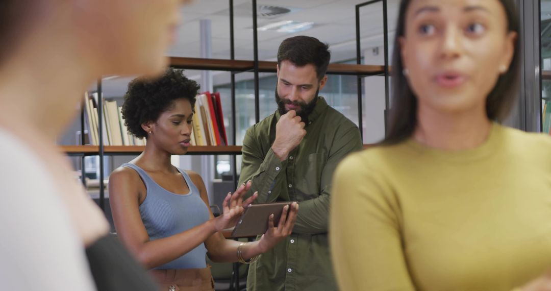 Coworkers Collaborating Around Tablet in Modern Open Office Discussing Project Strategy