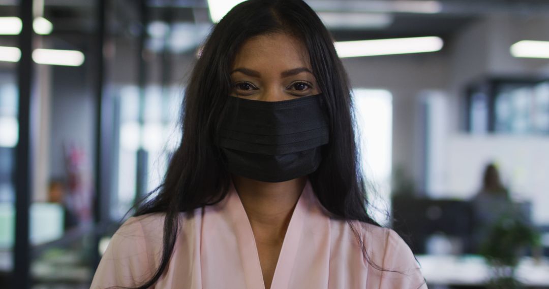 Confident Businesswoman Wearing Black Face Mask in Modern Office - Free Images, Stock Photos and Pictures on Pikwizard.com