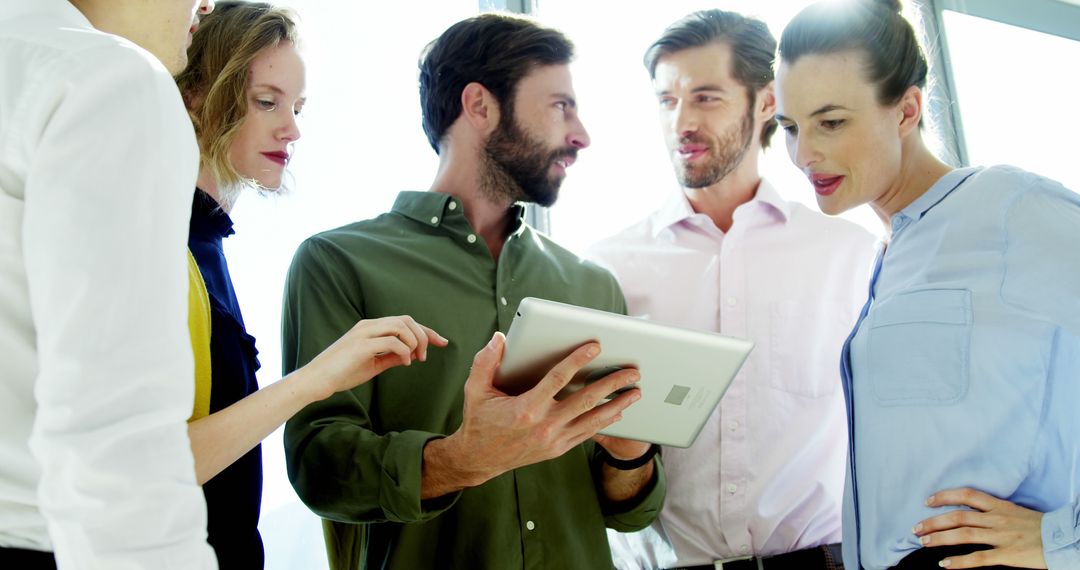 Professional Team Collaborating Over Digital Tablet in Modern Office