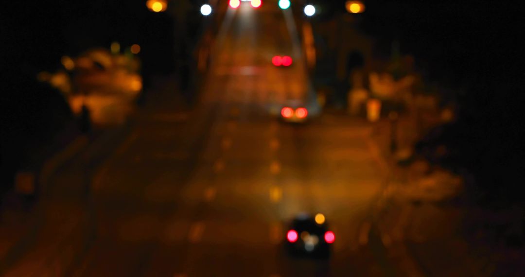 Blurry car taillights climbing illuminated urban hill at night with bokeh lights