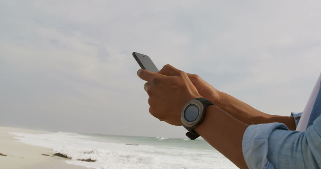 Man Using Smartphone on Beach with Ocean Background