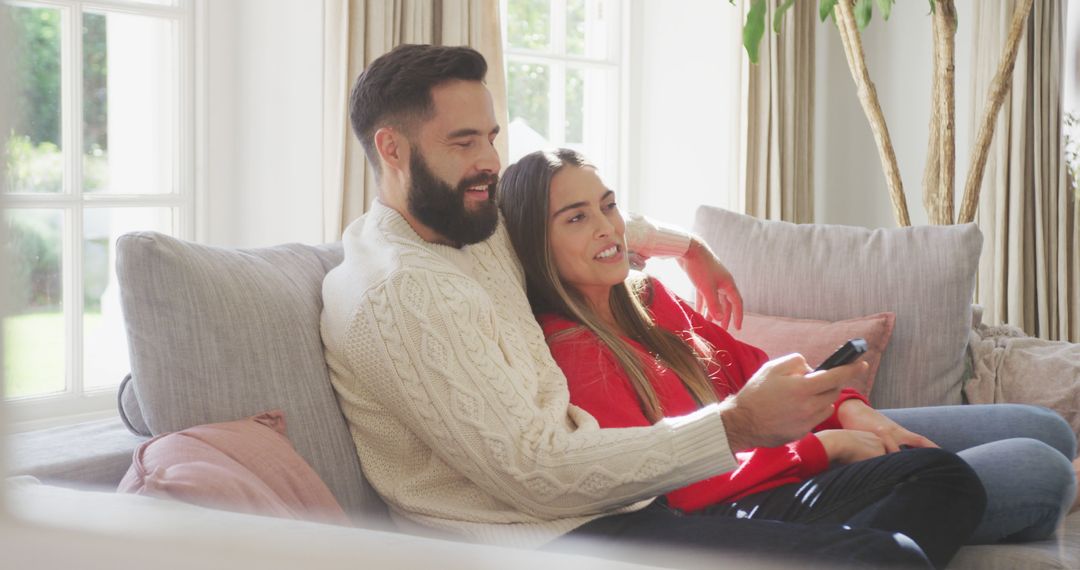 Image of happy caucasian couple siting on sofa and watching tv - Free Images, Stock Photos and Pictures on Pikwizard.com