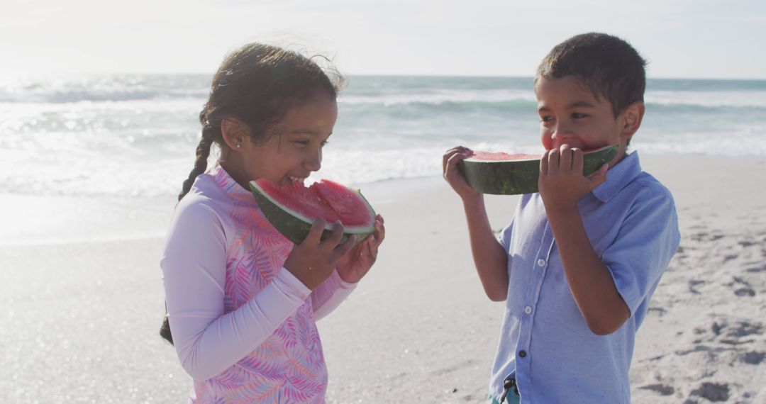 Smiling Siblings Enjoying Watermelon at Beachside